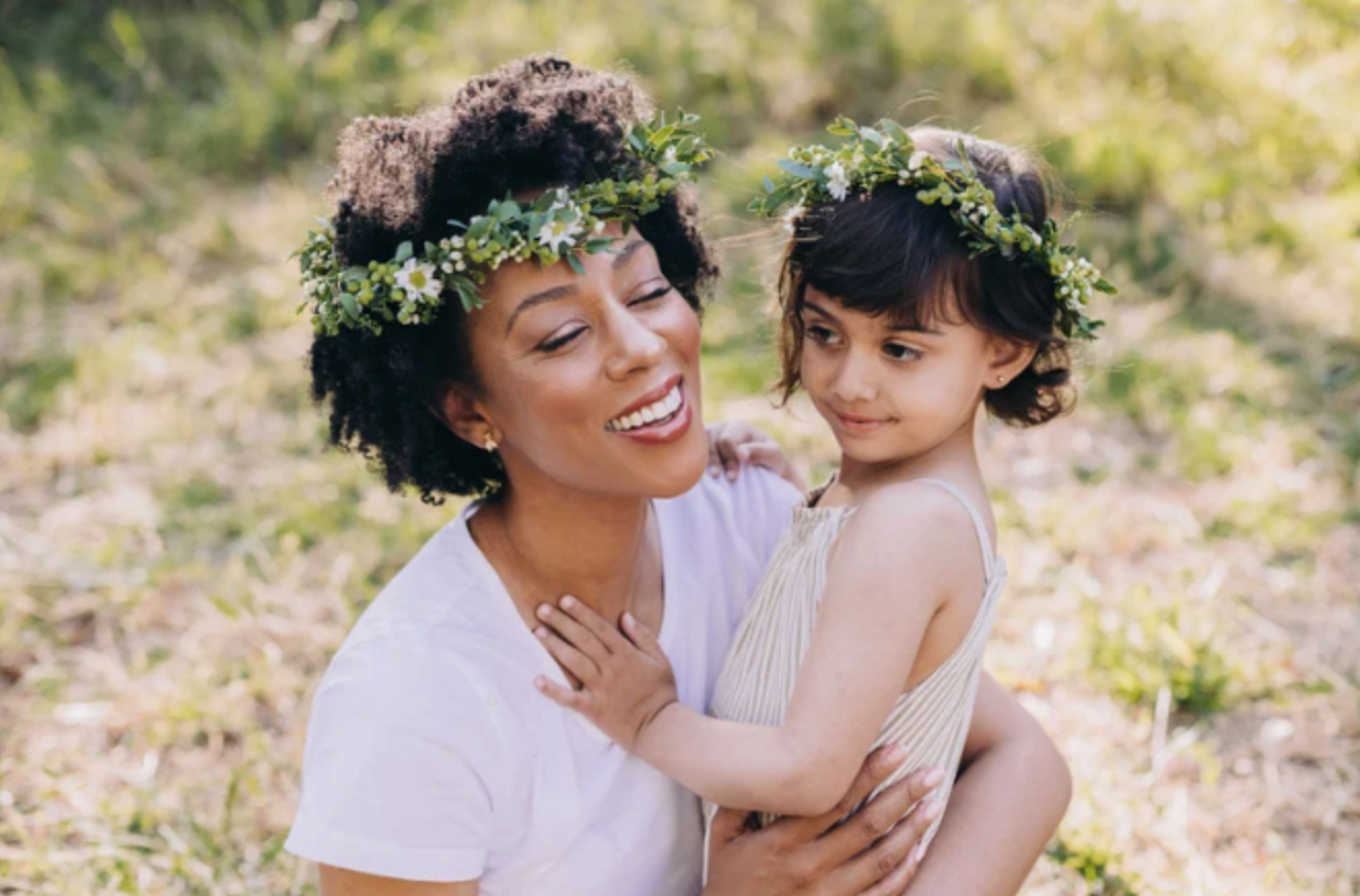 A woman is holding a little girl who is wearing a flower crown.