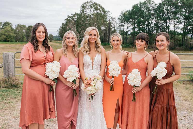 A bride and her bridesmaids are posing for a picture.