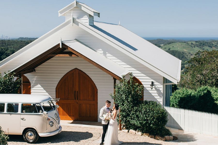 A bride and groom are standing in front of a white church.