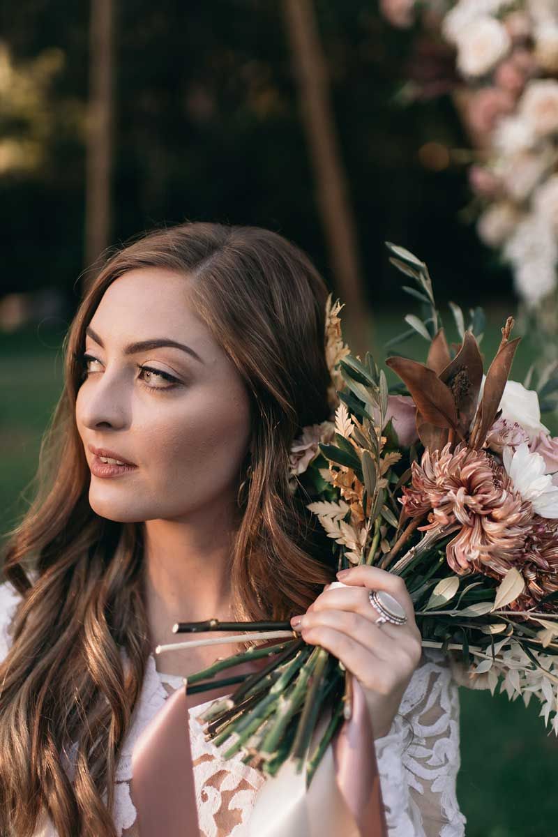 A woman in a white dress is holding a bouquet of flowers.
