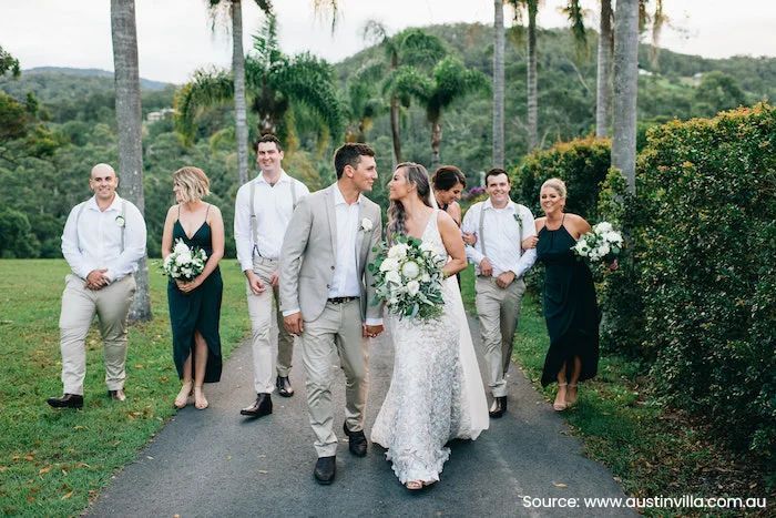 A bride and groom are standing on a beach holding hands.