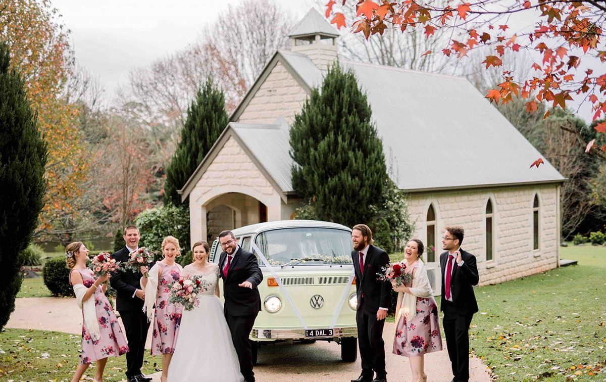 A bride and groom are kissing in front of a white van.