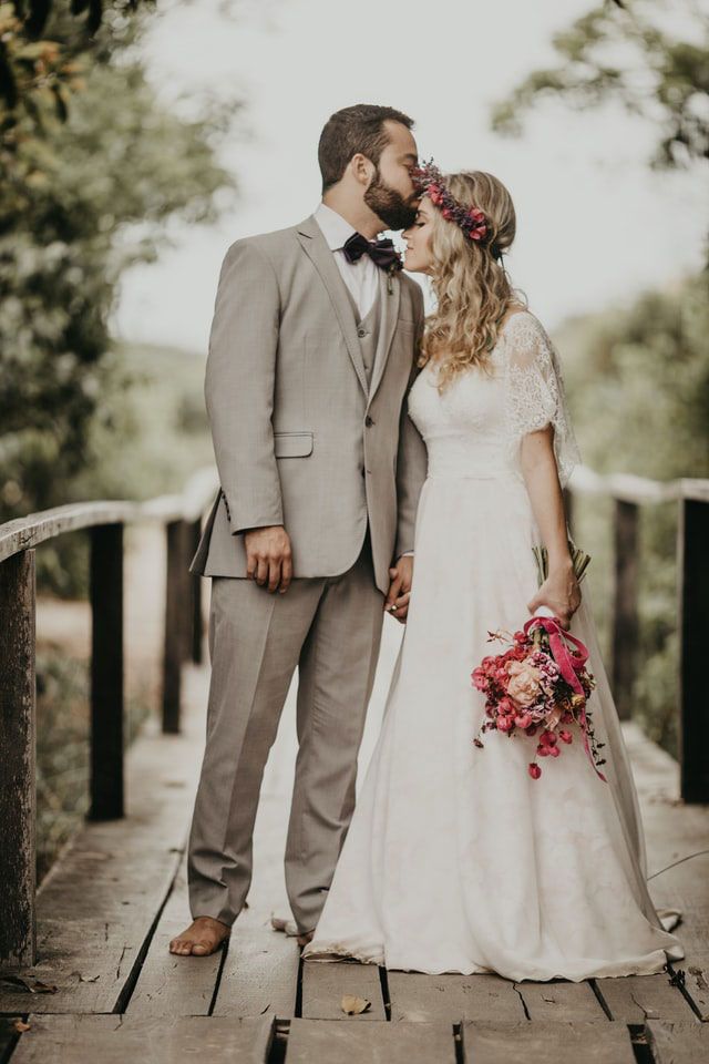 A bride and groom are kissing on a wooden bridge.
