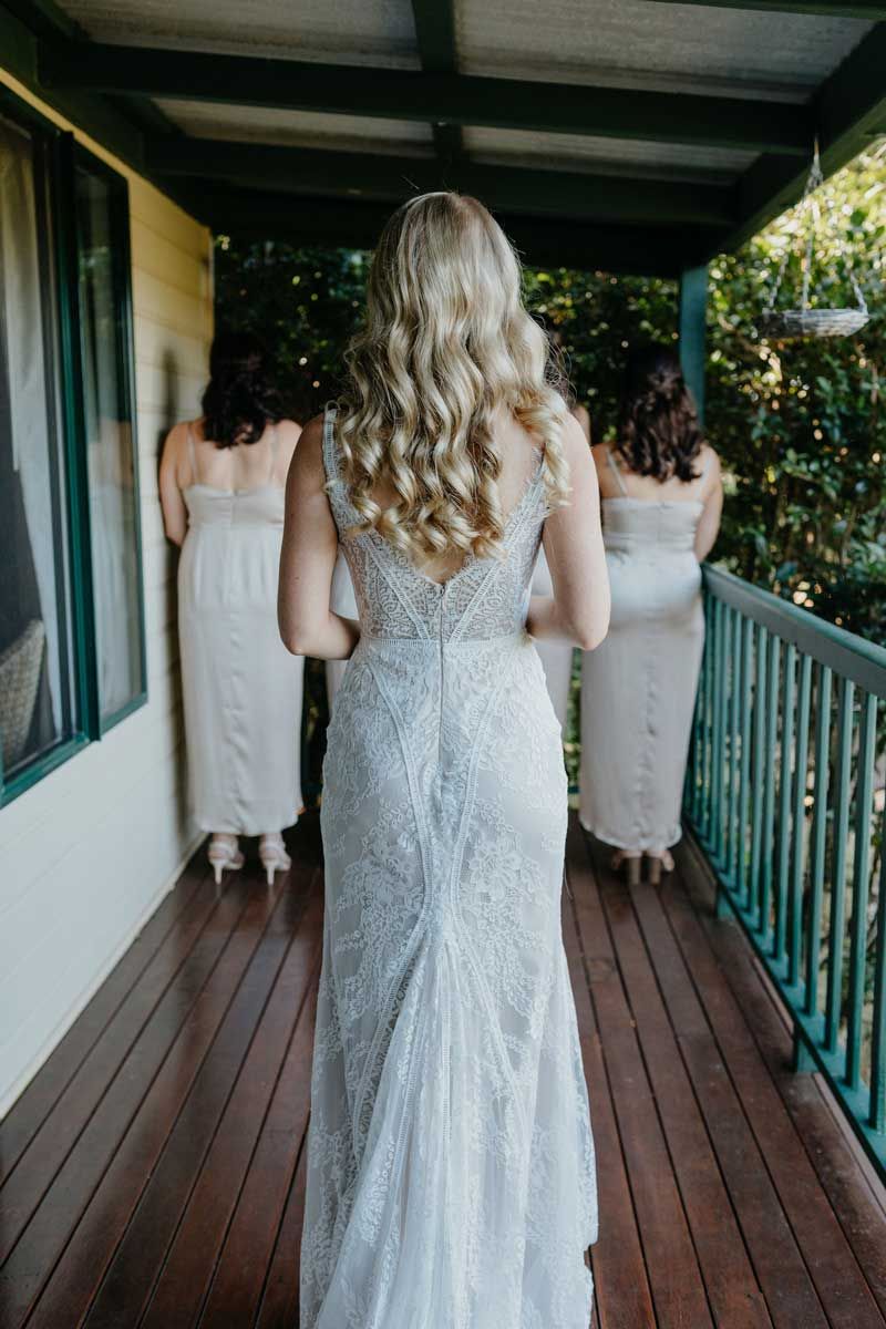A bride and her bridesmaids are standing on a balcony.