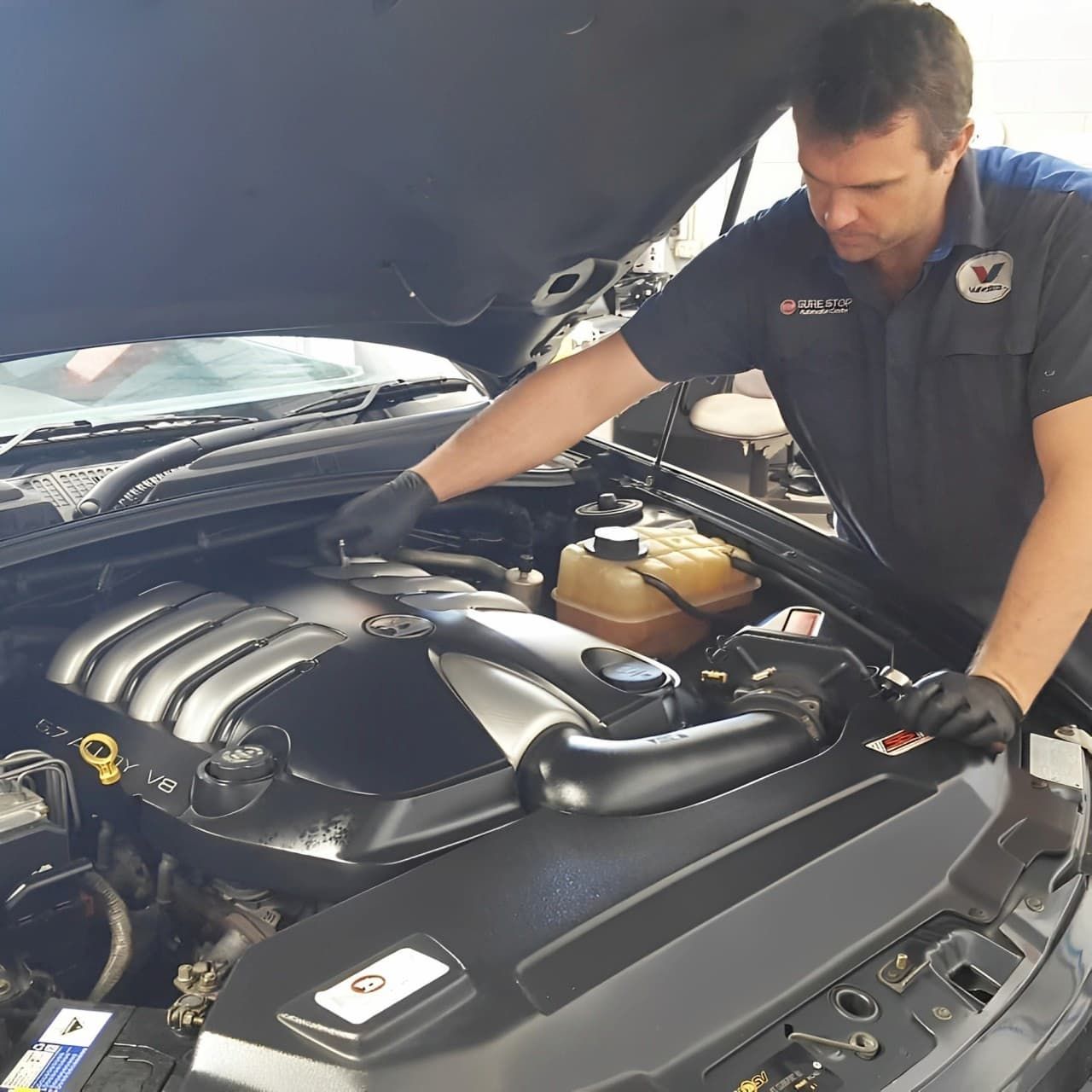 A man is working on the engine of a car  — Sure Stop Automotive Centre In Nerang, QLD