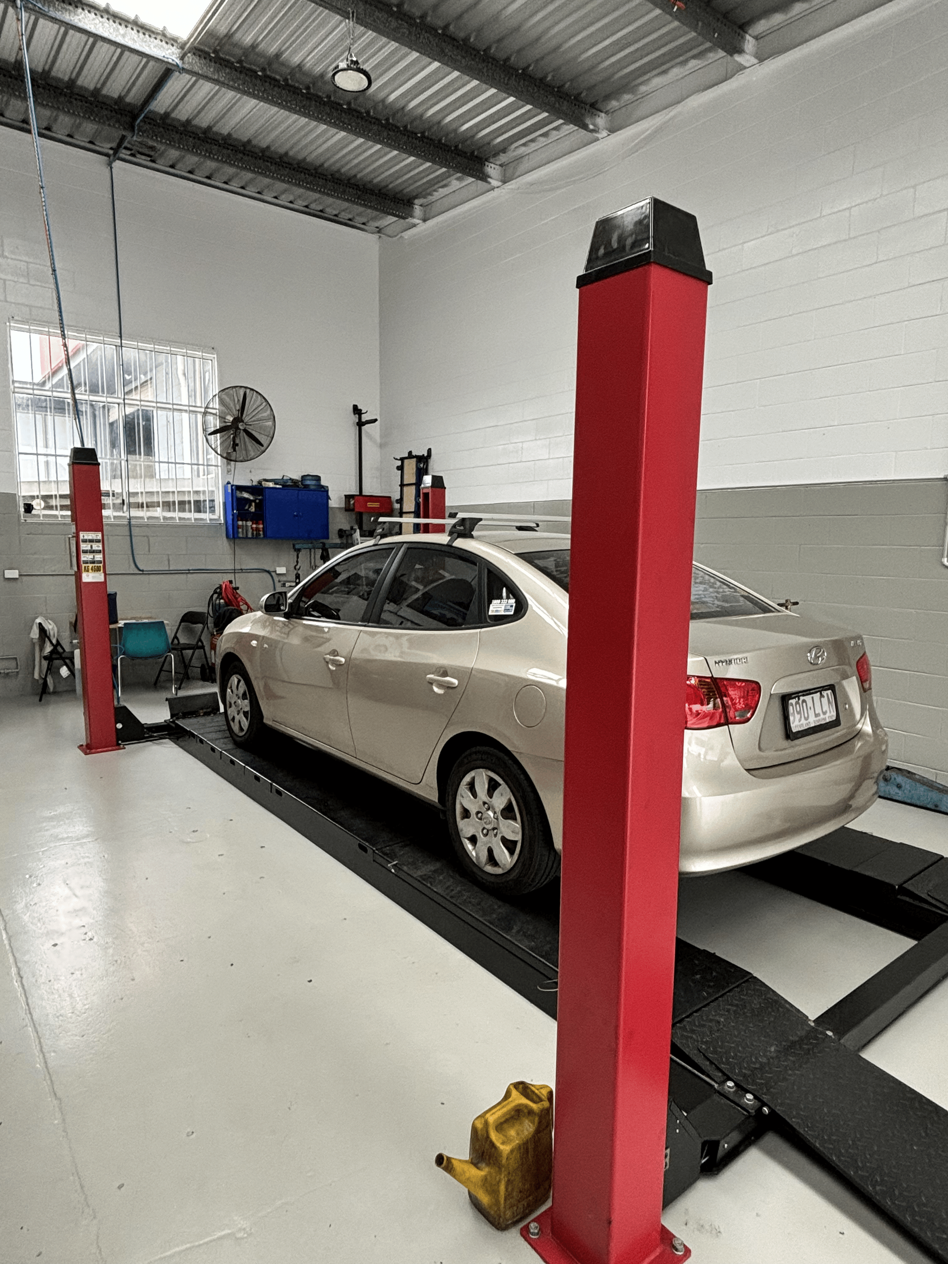 A car is sitting on a lift in a garage.  — Sure Stop Automotive Centre In Nerang, QLD