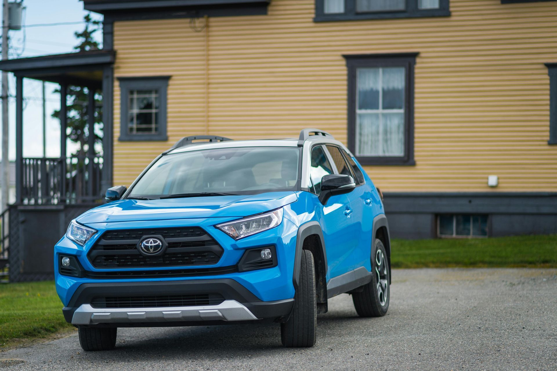 A blue toyota hybrid rav4 is parked in front of a yellow house. — Sure Stop Automotive Centre In Nerang, QLD