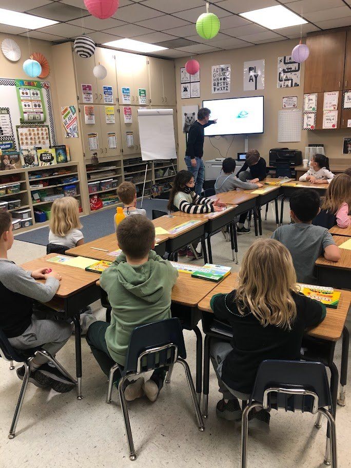 A group of children are sitting at desks in a classroom.