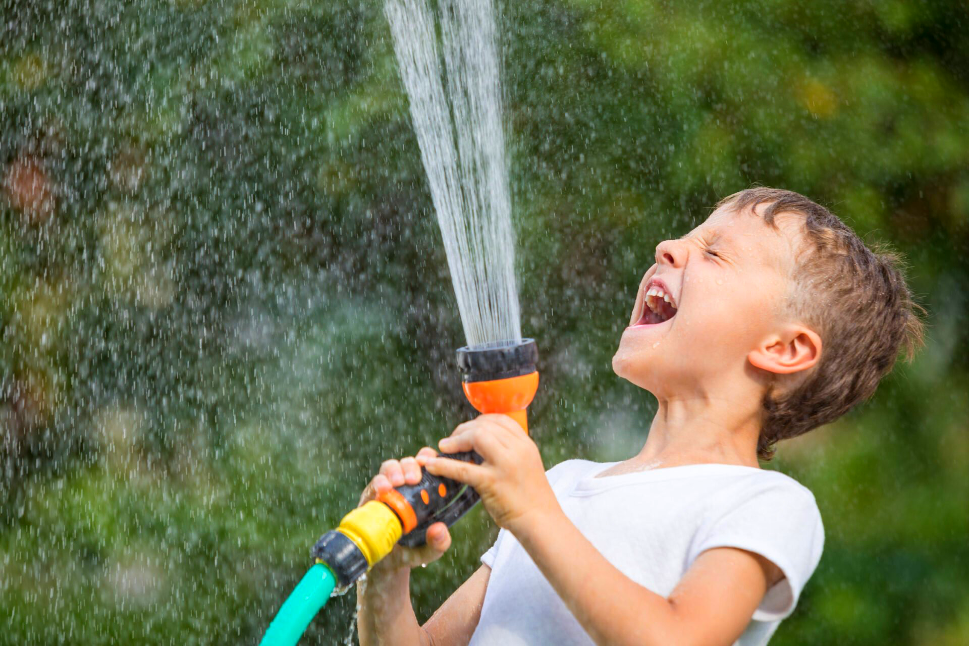 A young boy is spraying water from a hose.