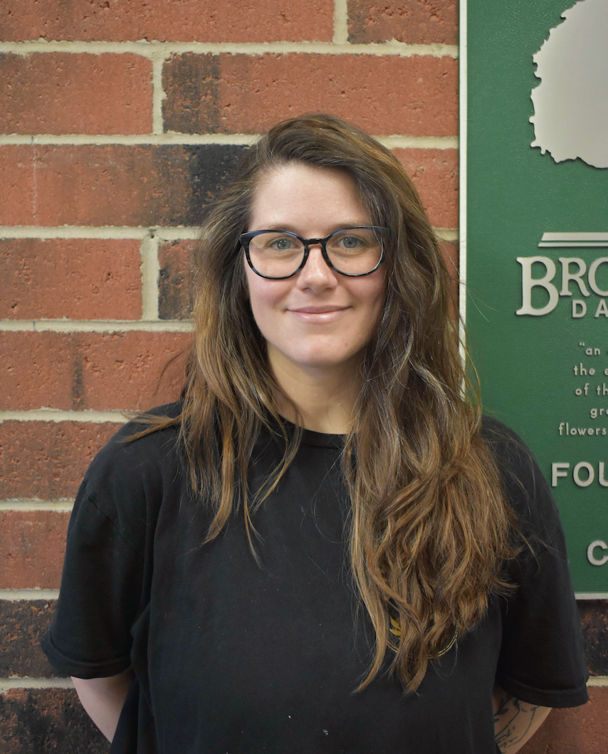 A woman wearing glasses and a necklace is smiling for the camera.