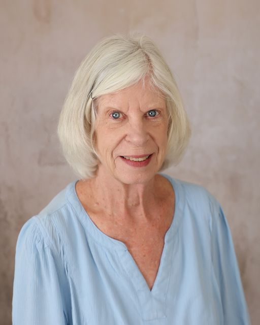 A woman wearing a brookridge day school shirt is smiling in front of a brick wall.