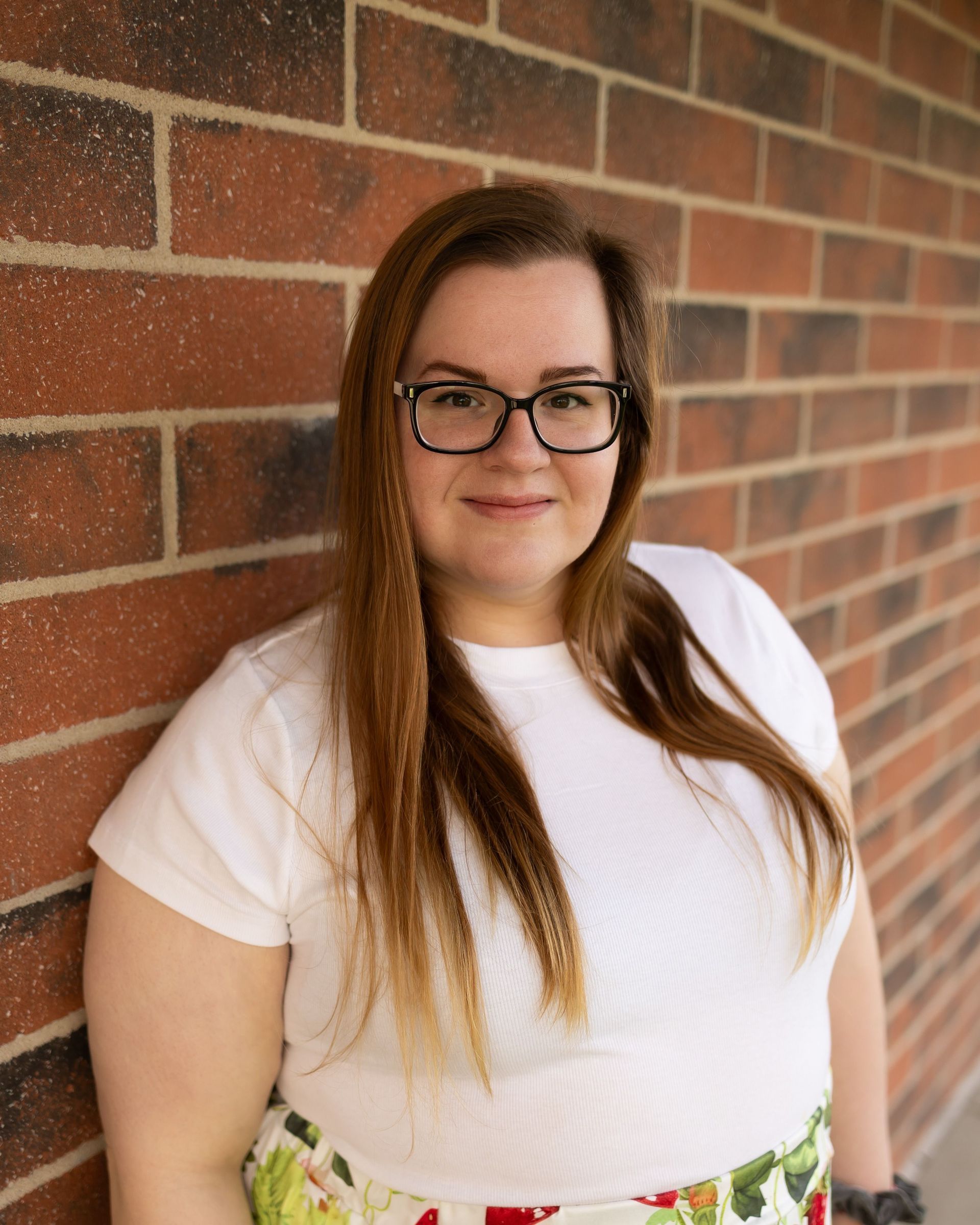 A woman wearing glasses and a necklace is smiling for the camera.