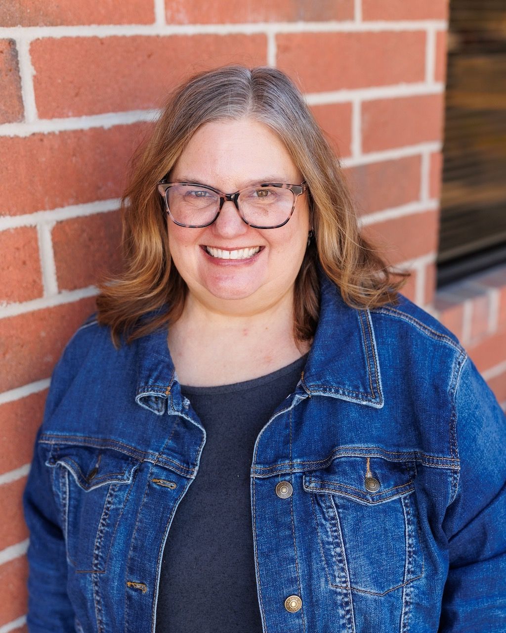 A woman in a blue floral shirt is smiling for the camera.
