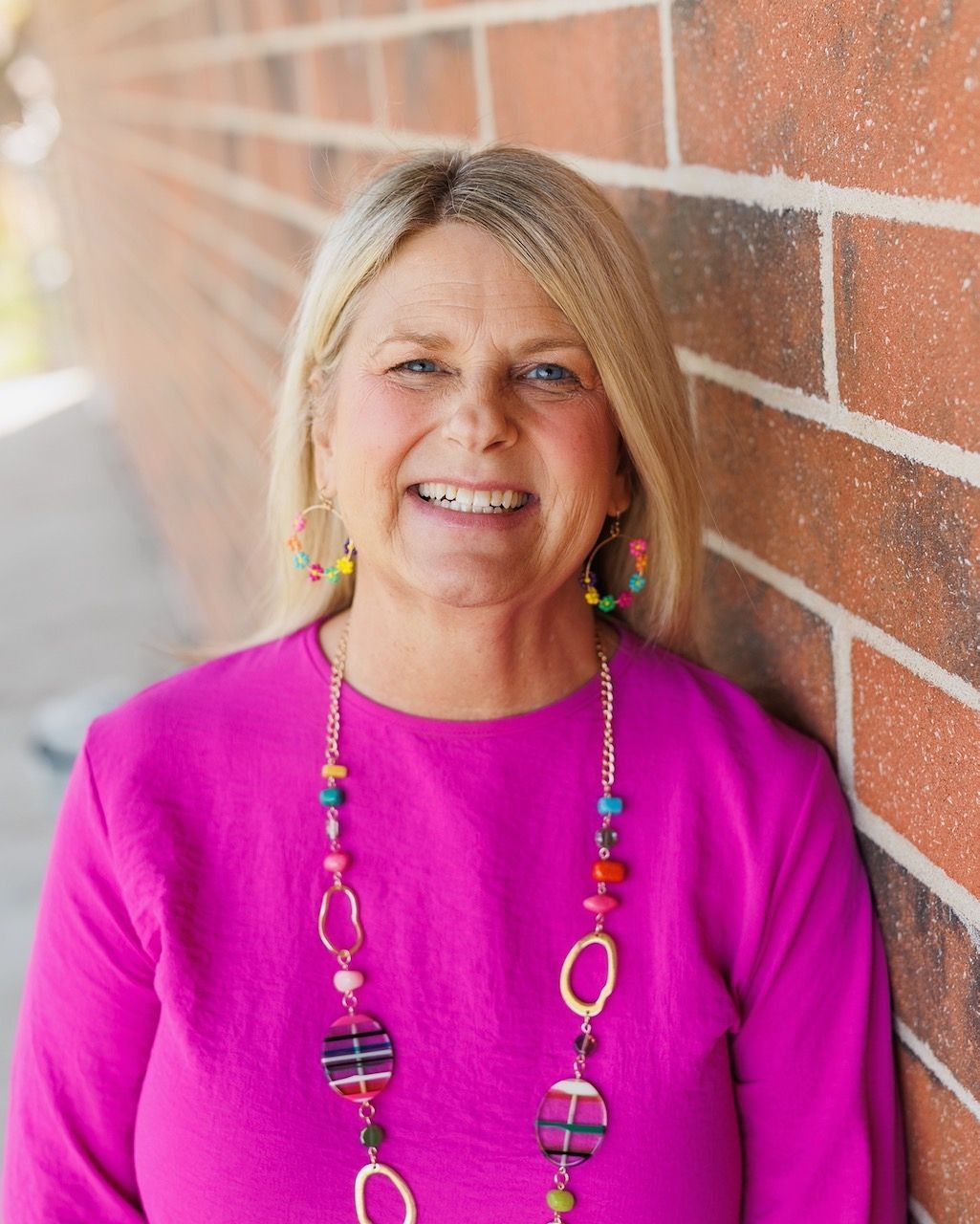 A woman in a red and black floral dress is smiling for the camera.
