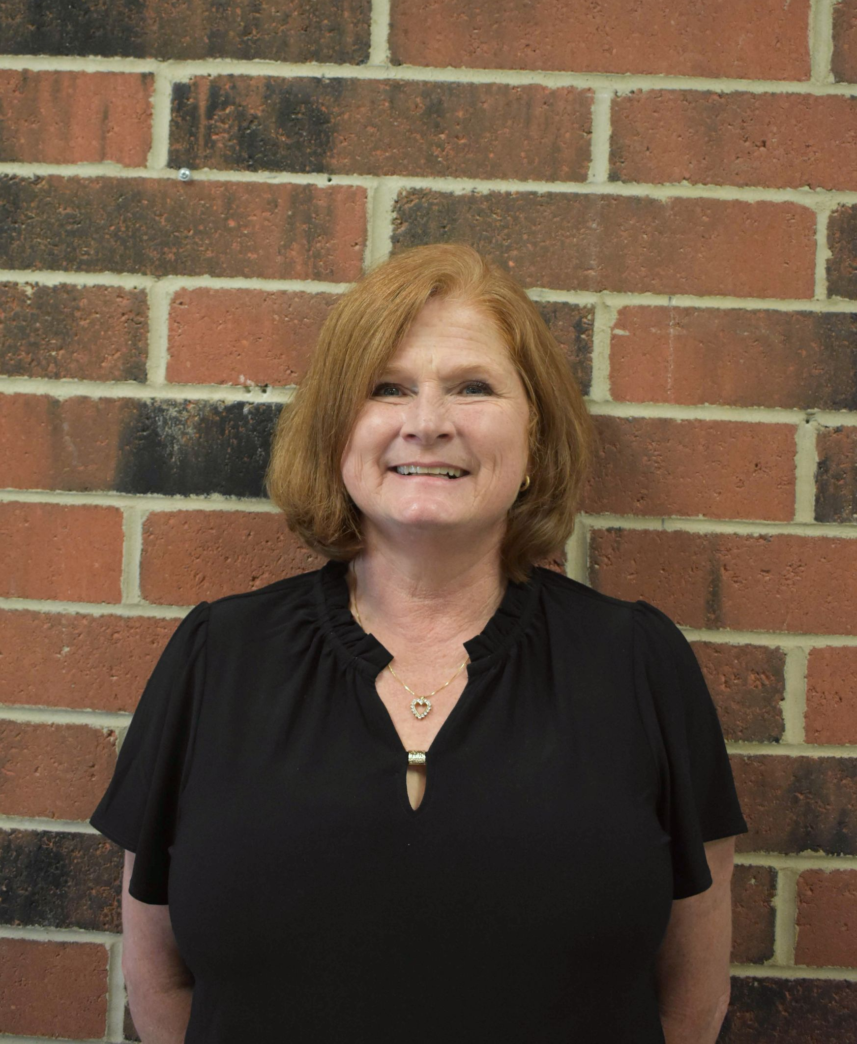 The woman is wearing a black shirt and smiling for the camera.