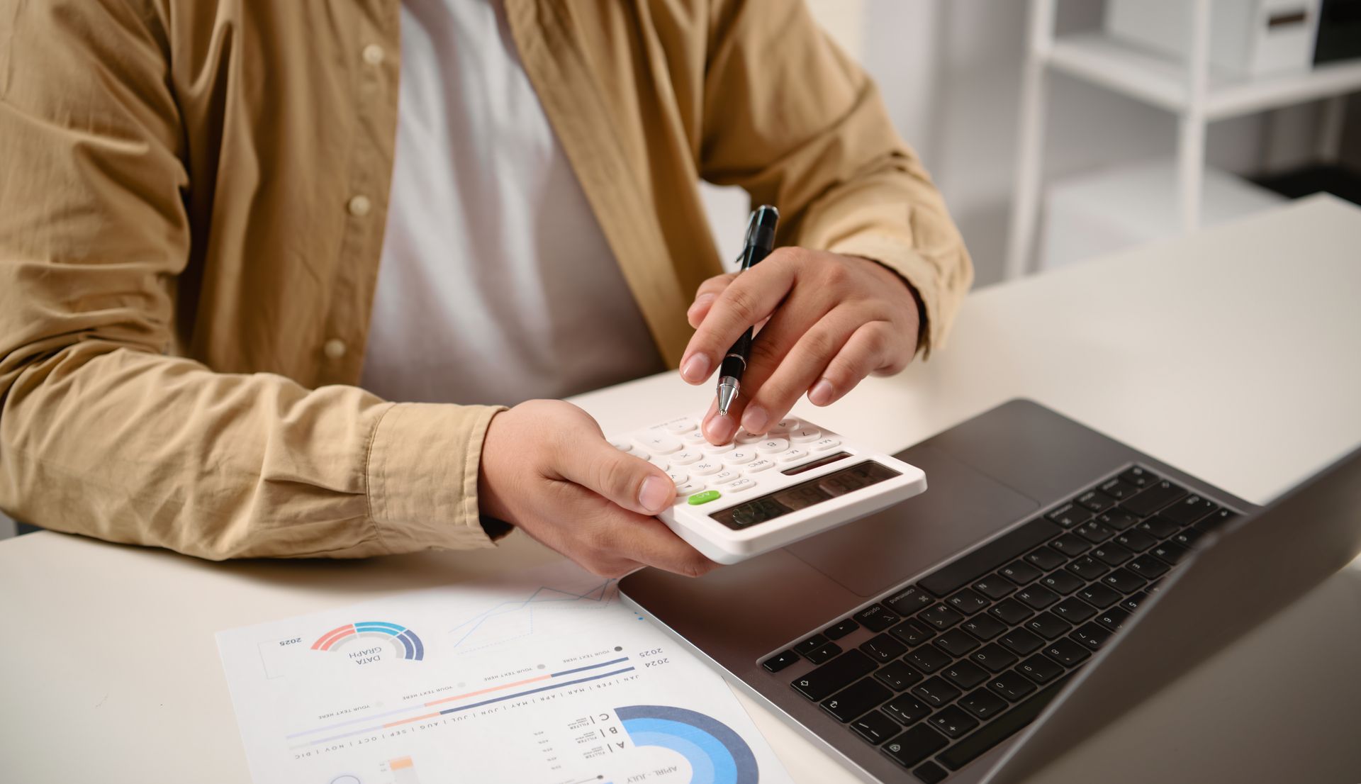 Businessman analyzing financial report with calculator and laptop.