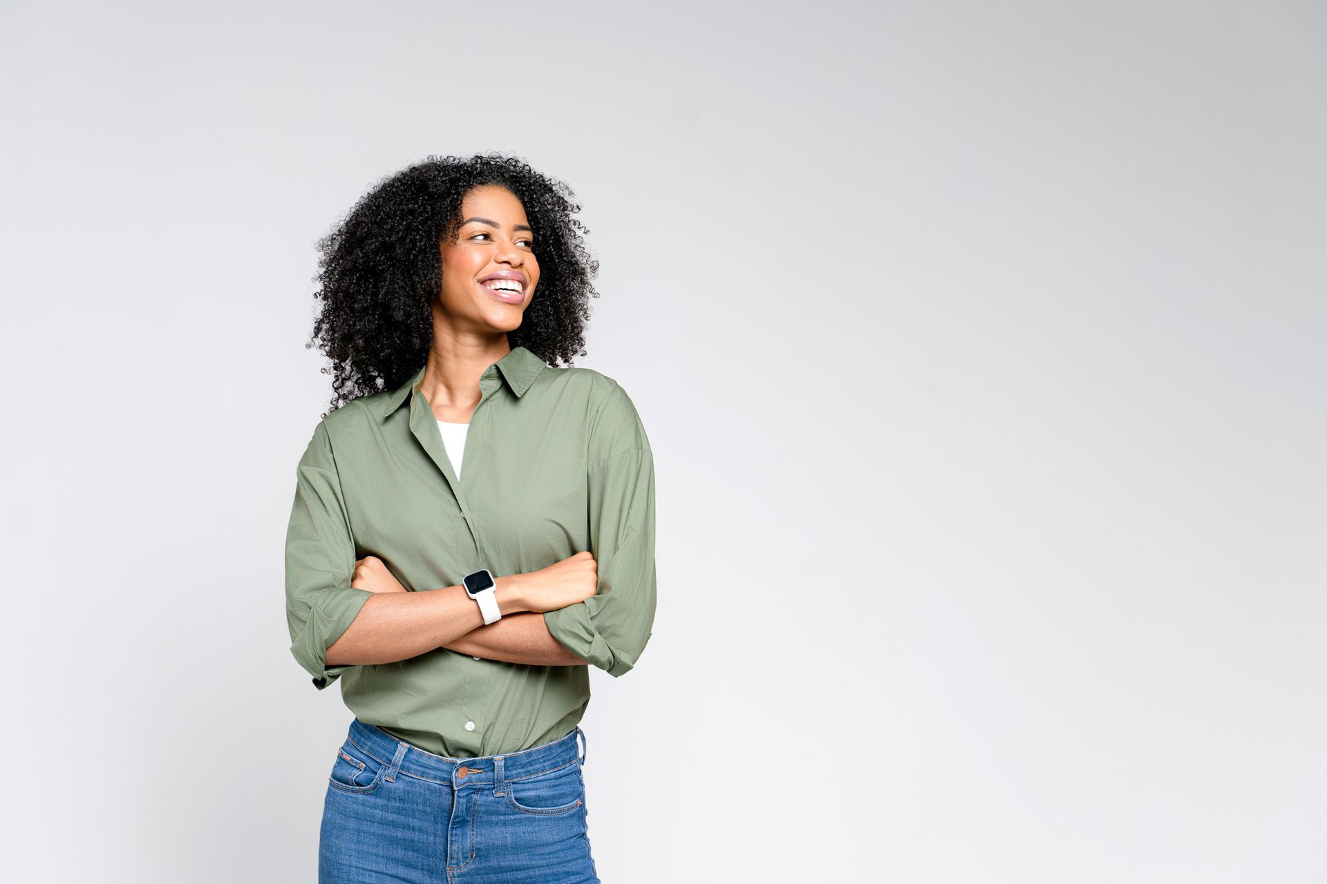 A woman in a green shirt and blue jeans is standing with her arms crossed and smiling. A woman in a green shirt and blue jeans is standing with her arms crossed and smiling.