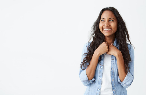 A woman in a denim shirt is smiling and looking up.