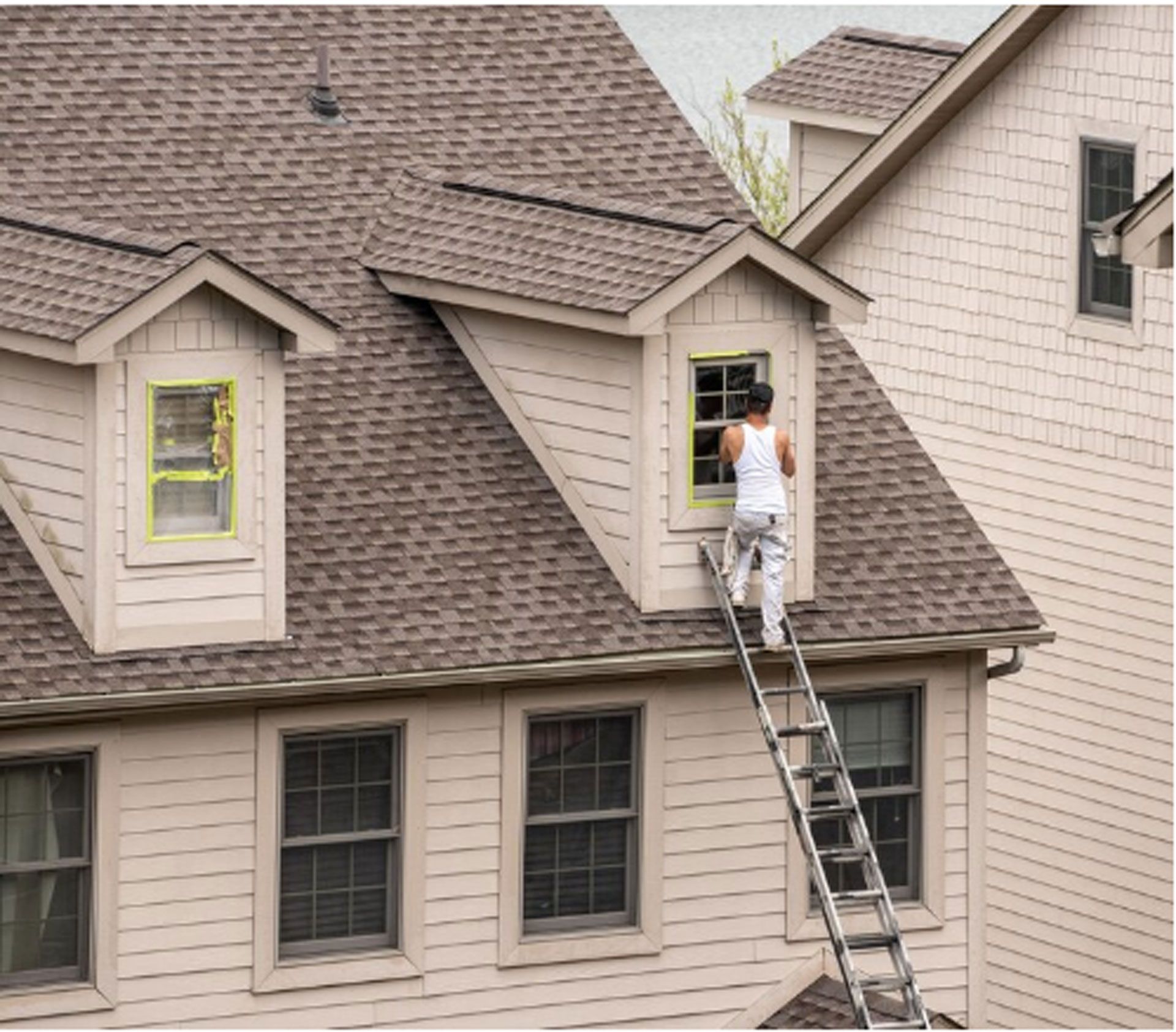 A man is standing on a ladder on the side of a house