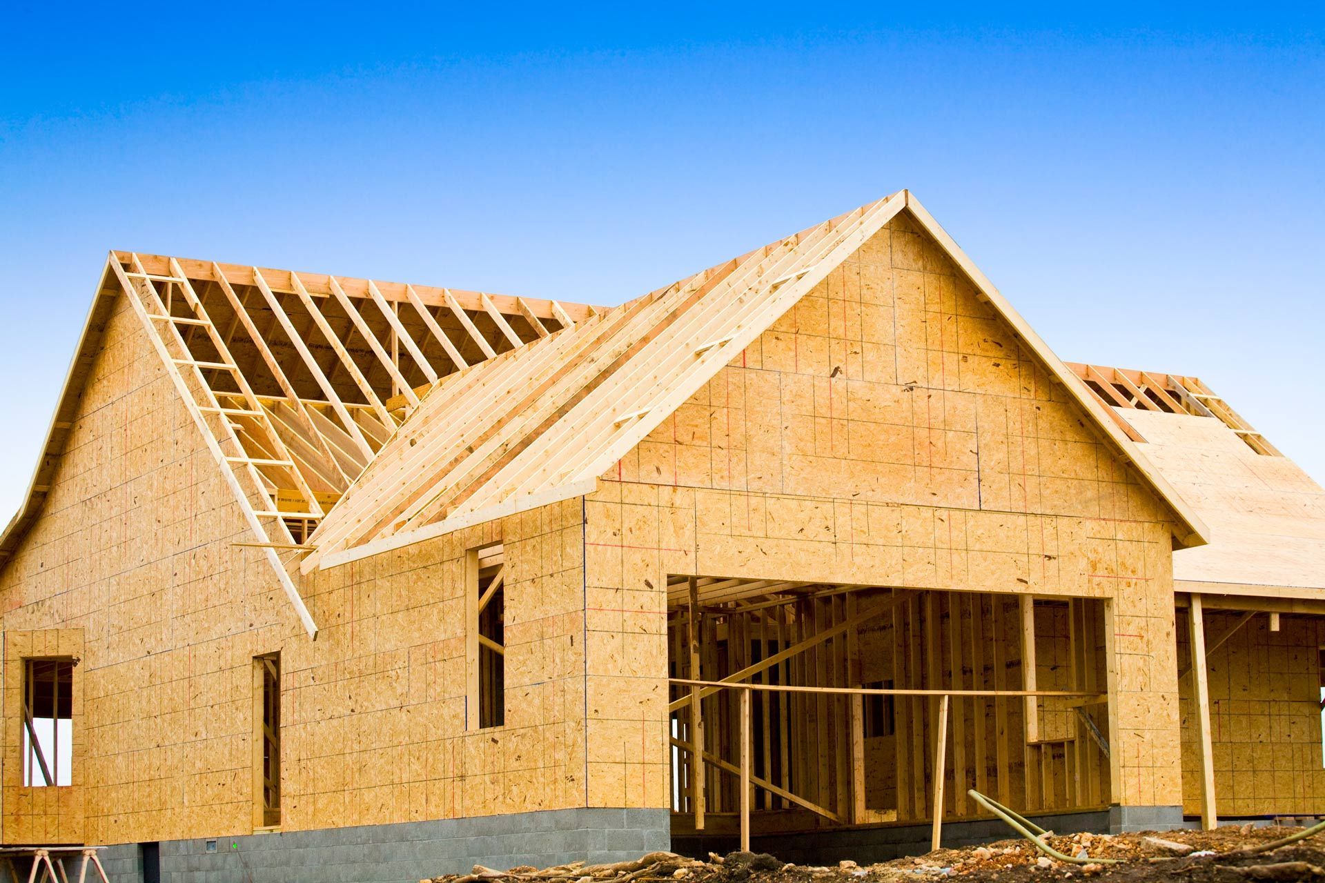 A wooden house is being built with a blue sky in the background