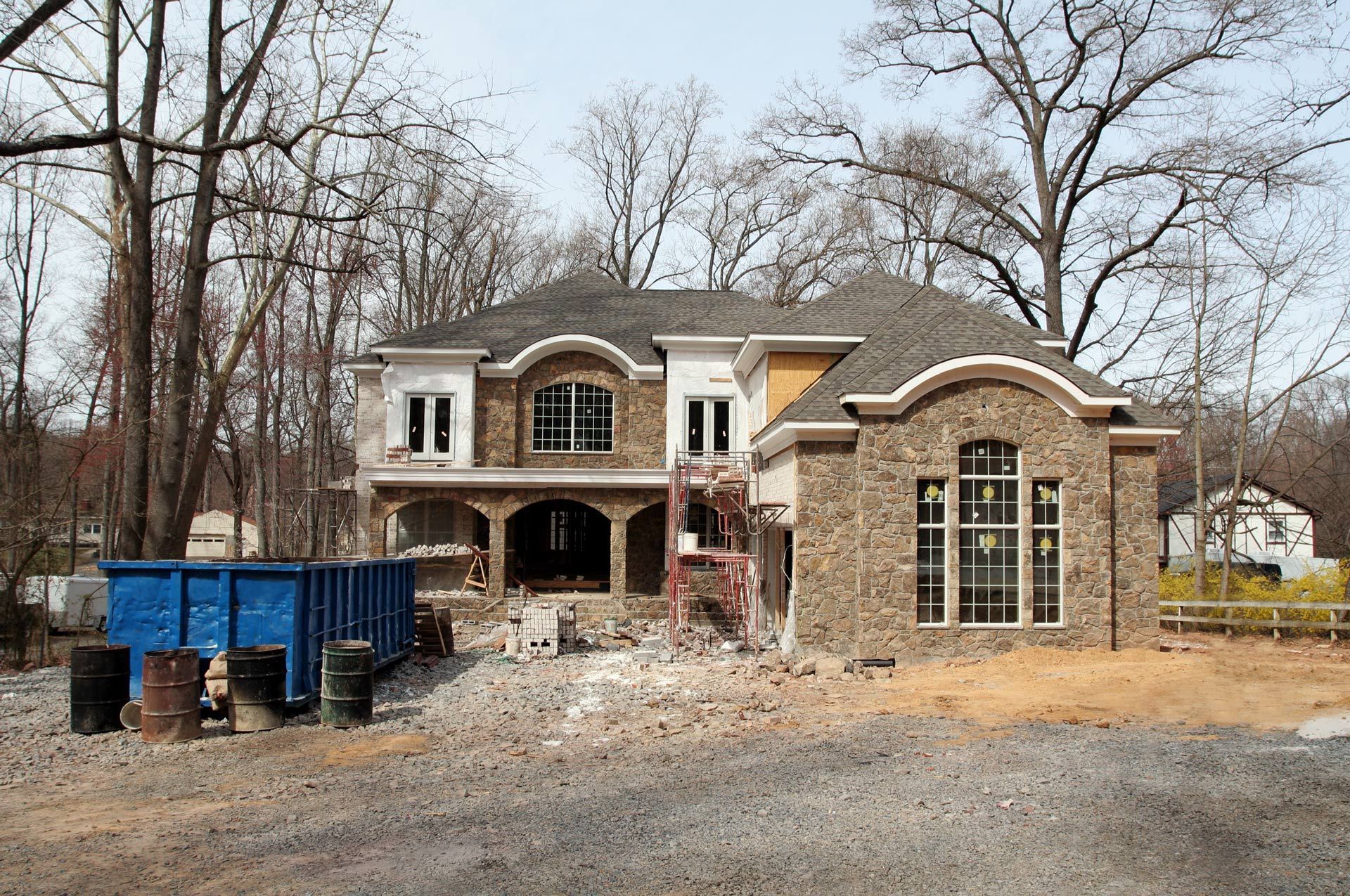 A large house under construction with a blue dumpster in front of it
