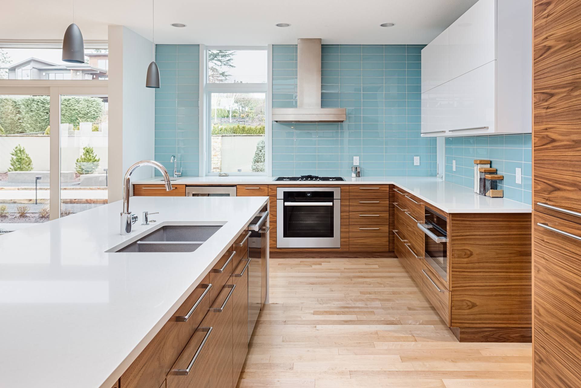 A kitchen with wooden cabinets , white counter tops , and blue tiles