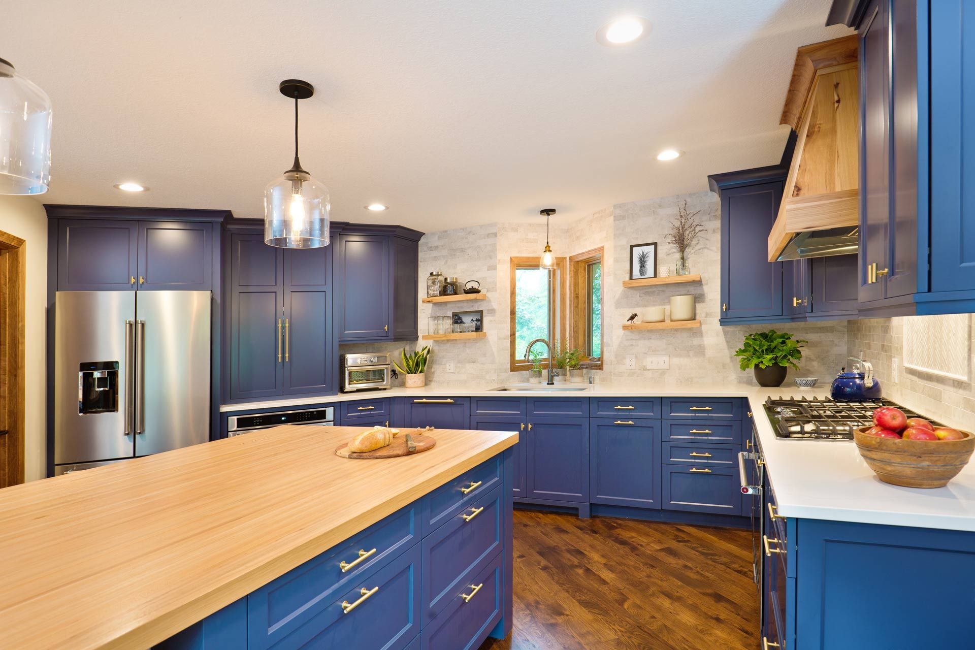 A kitchen with blue cabinets , stainless steel appliances , and a large island