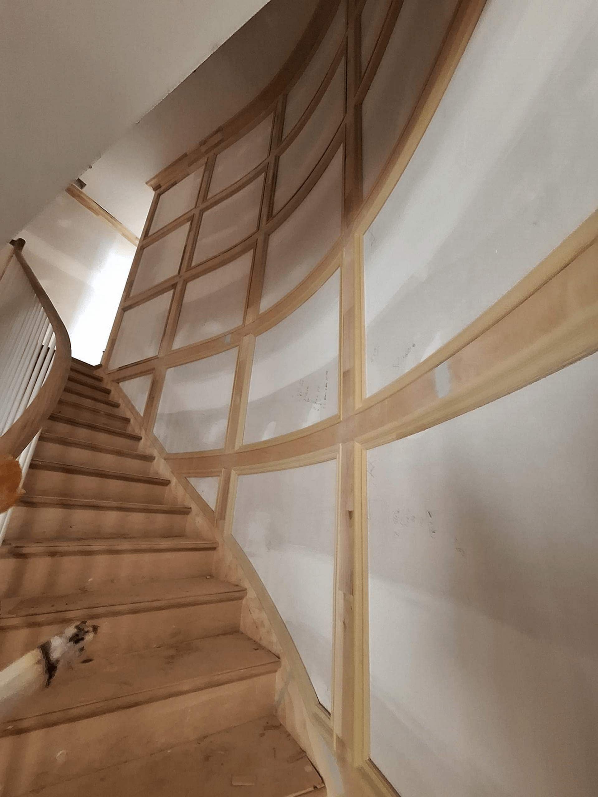 A wooden staircase with a white wall behind it