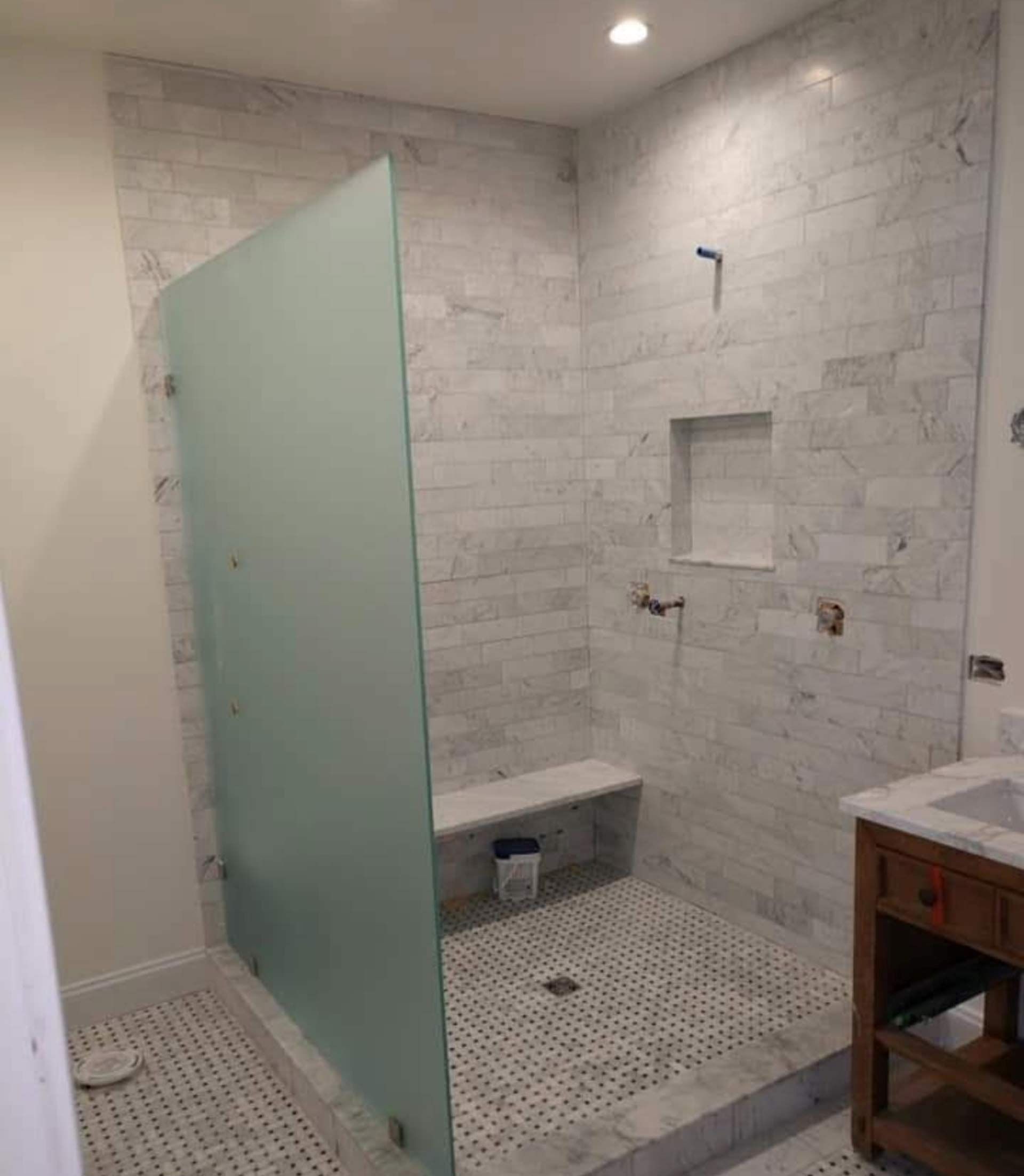 A bathroom with a walk in shower and a sink