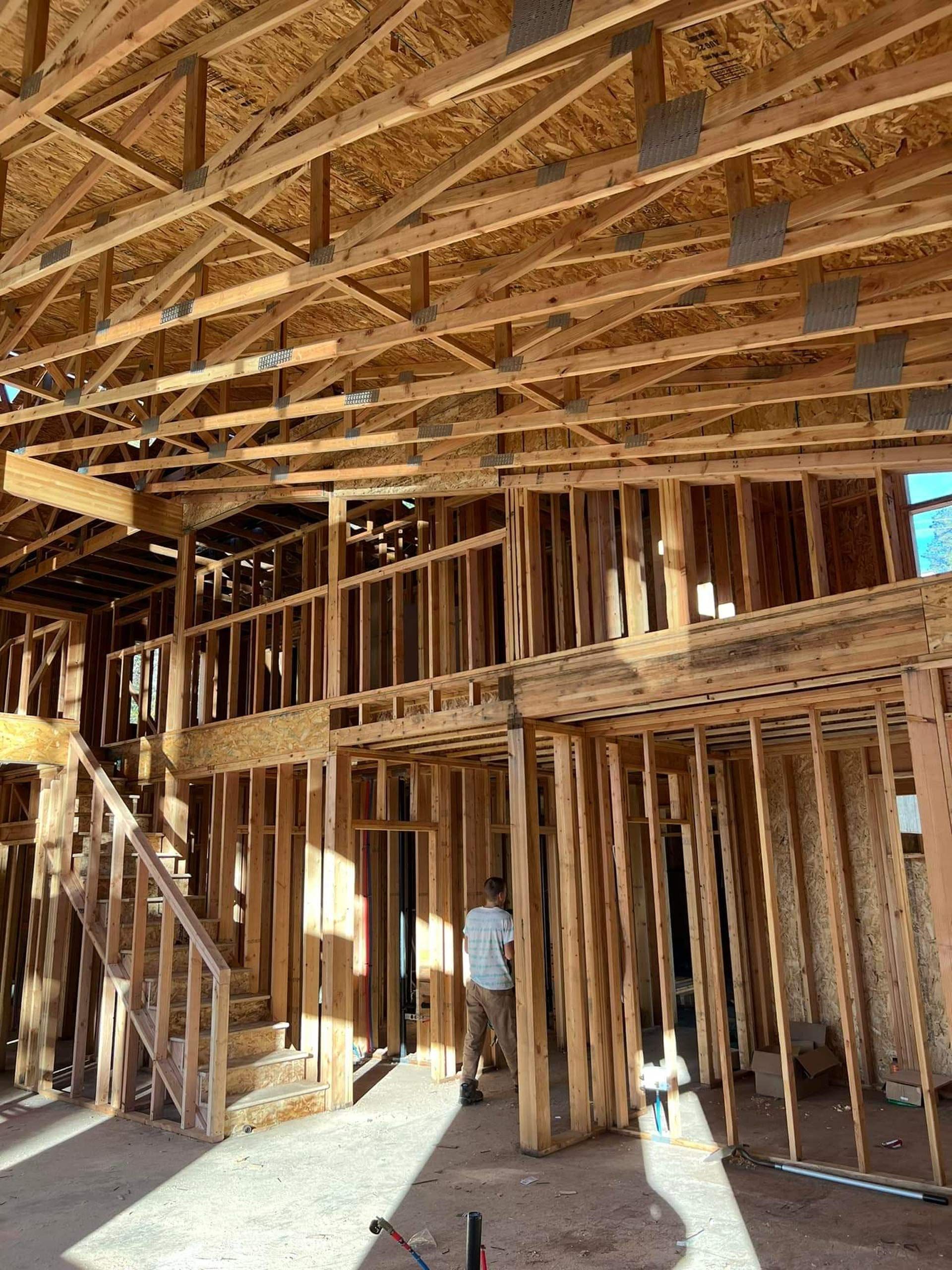 A man is standing in the middle of a house under construction