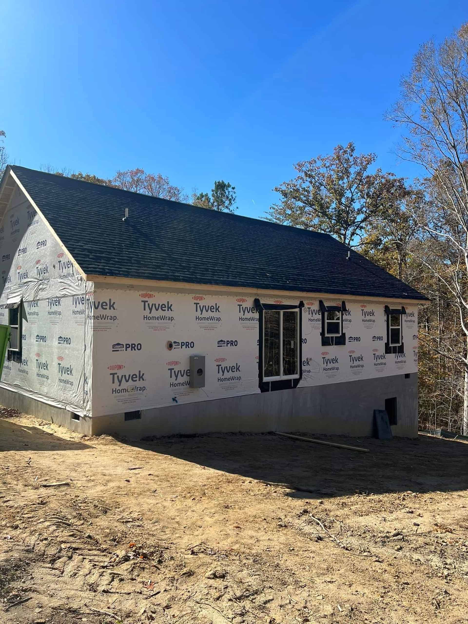 A small house with a black roof is sitting on top of a dirt hill