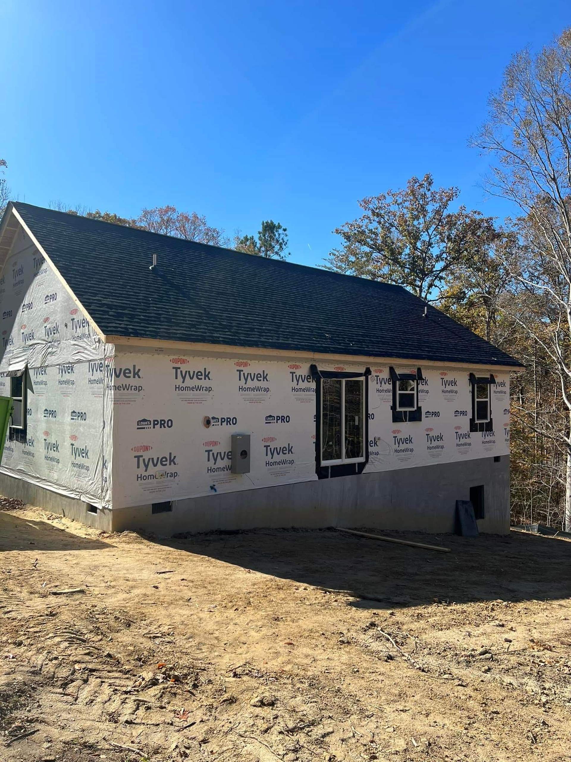 A small house with a black roof is sitting on top of a dirt hill