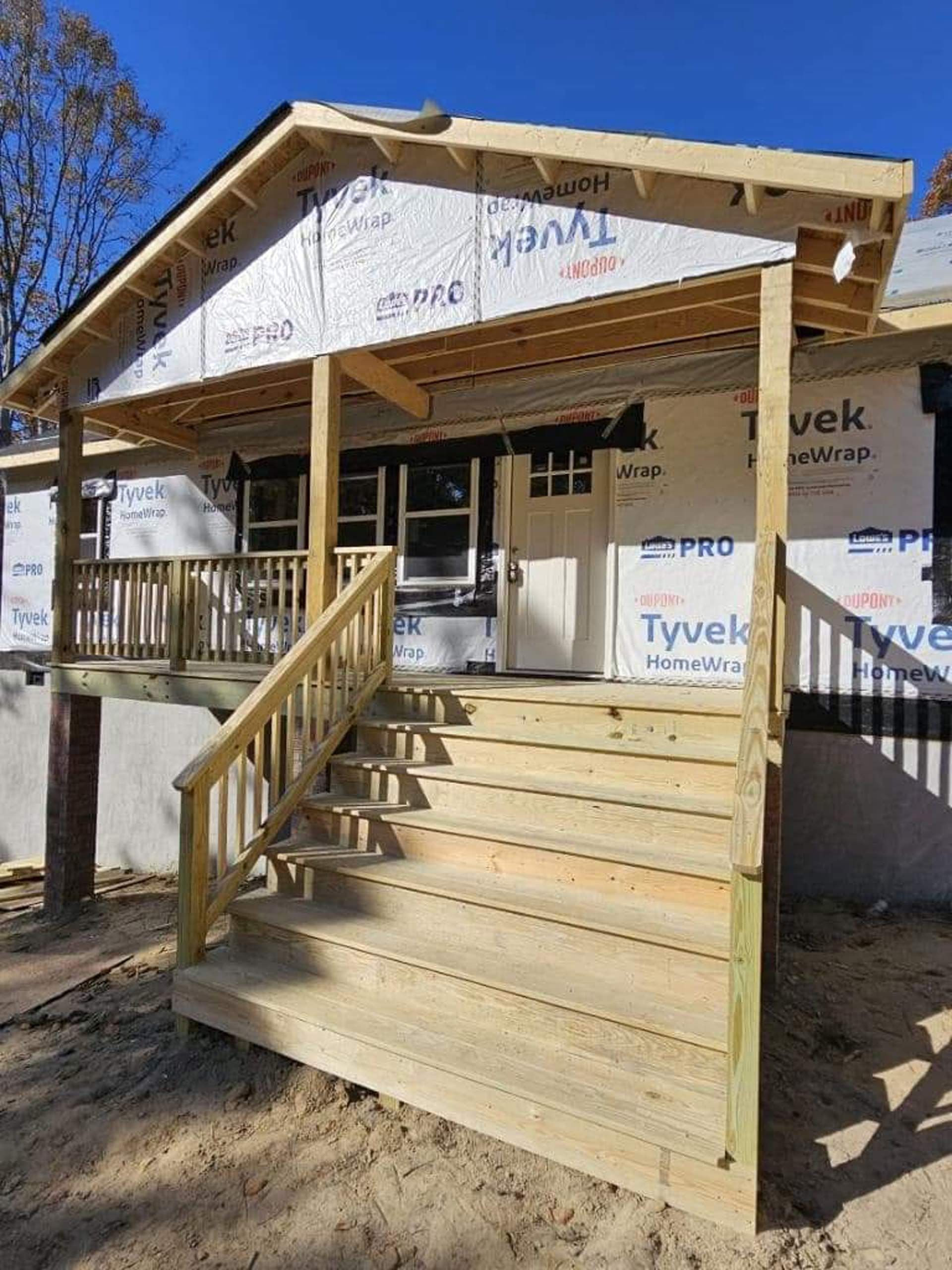 A house under construction with a wooden deck and stairs