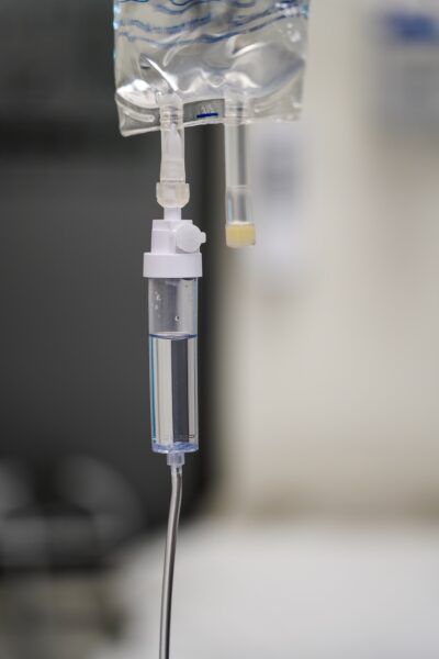 IV drip bag with clear fluid, suspended in a clinical setting.