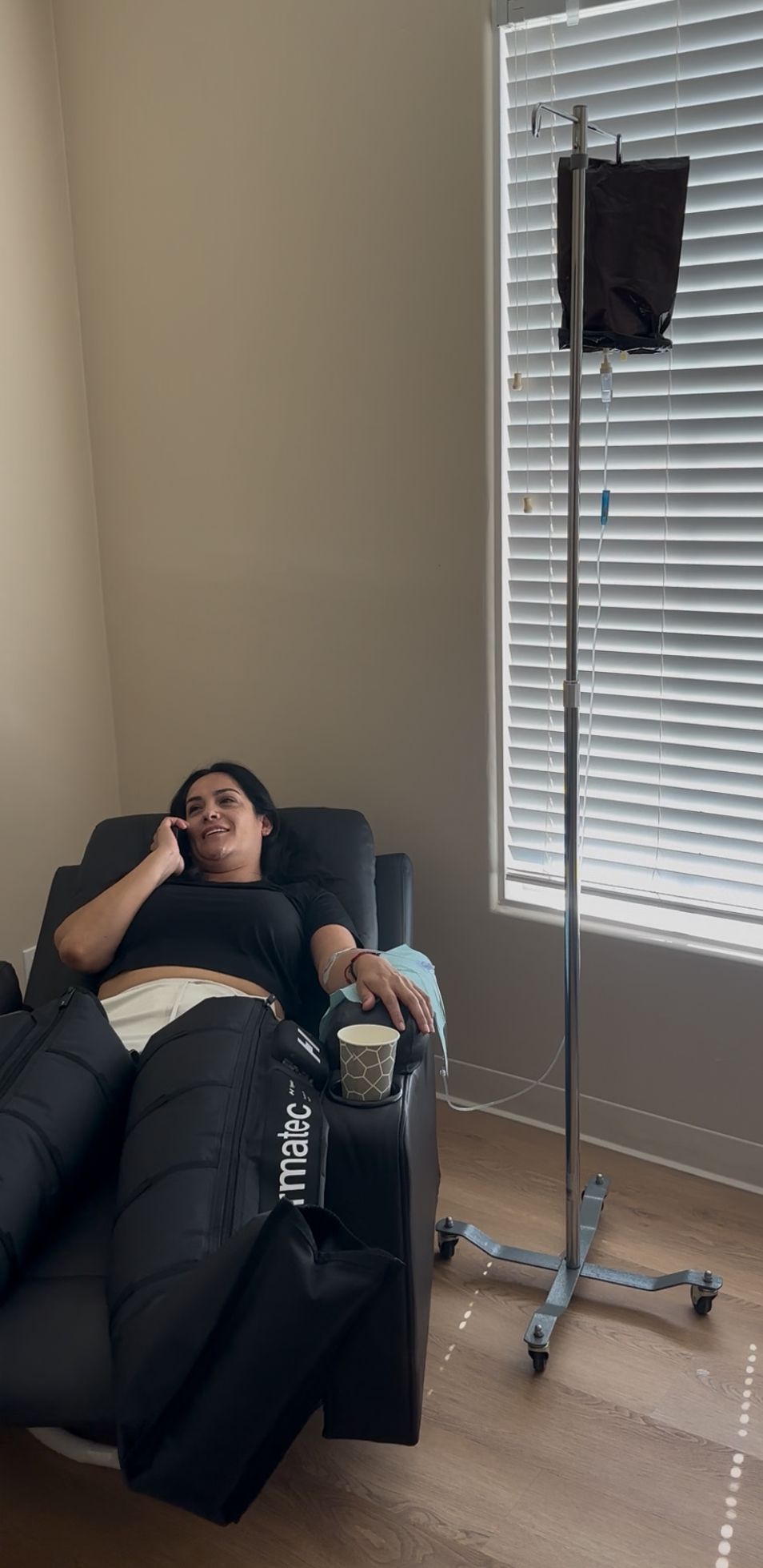 Person receiving IV fluids in a medical setting, nurse visible.