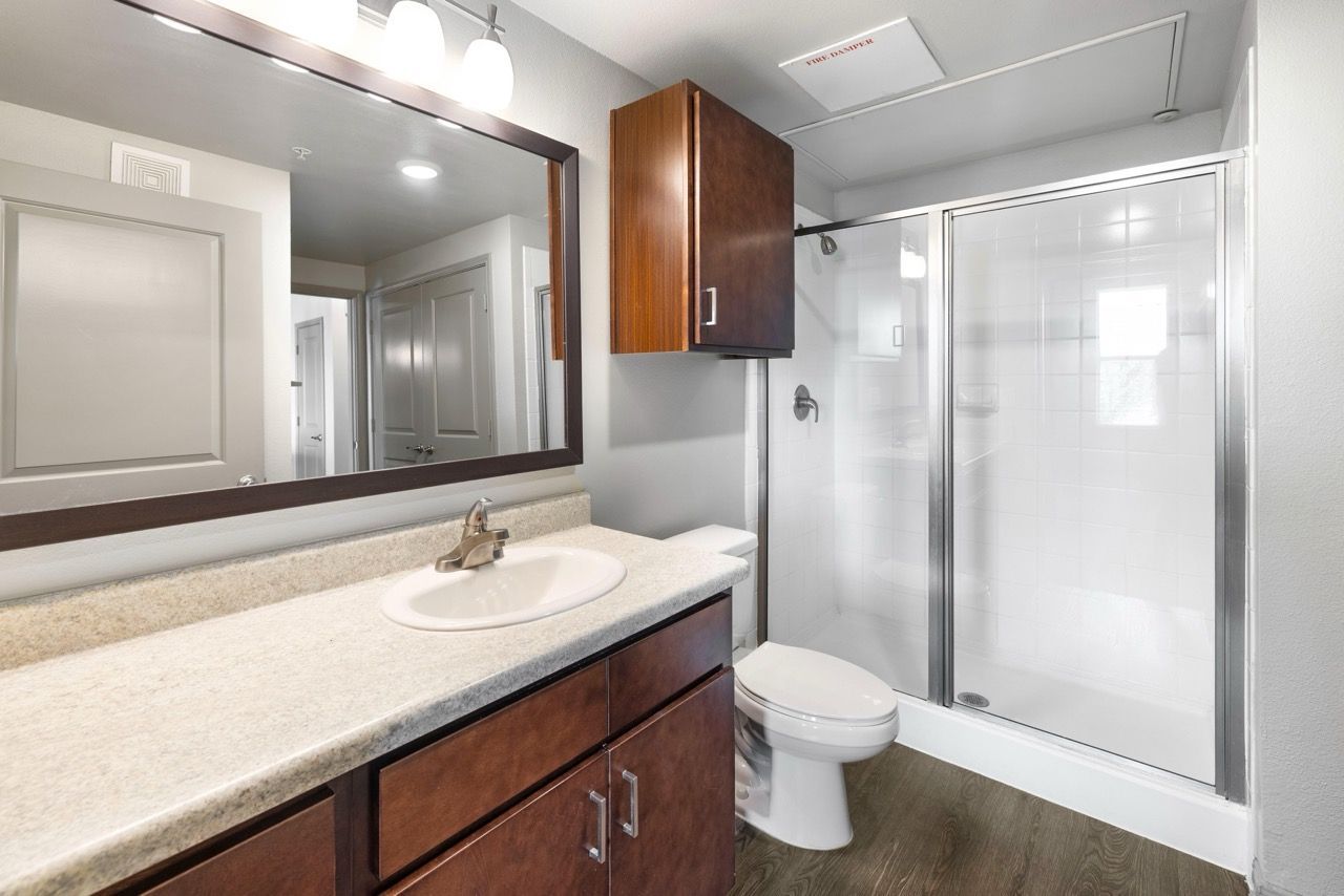 Bathroom with vanity, sink, mirror, and a glass shower in a modern apartment.