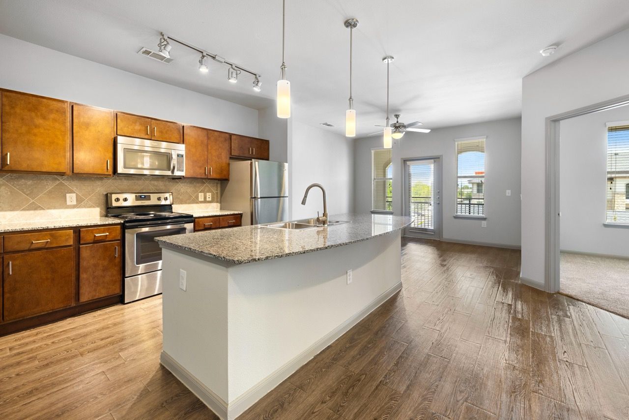 Open-concept kitchen with island, granite countertops, and stainless-steel appliances.