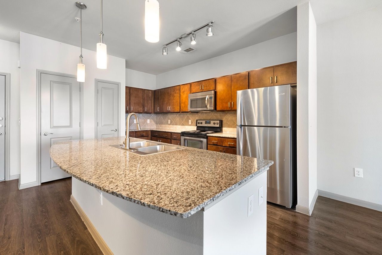 Open-concept kitchen with granite island, stainless steel appliances, and dark wood cabinets.