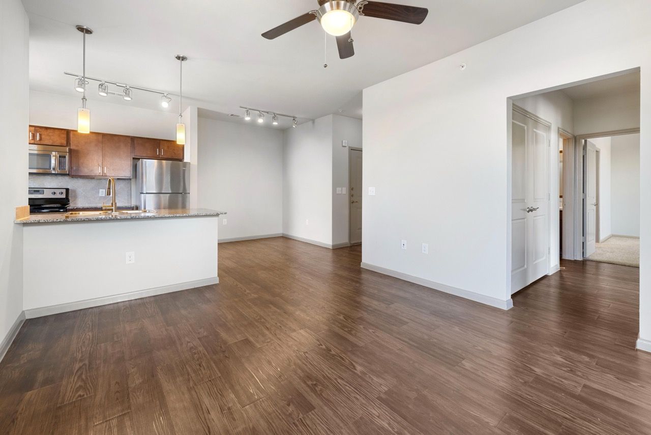 Open-concept living area with kitchen island, stainless steel appliances, and wood-look flooring.