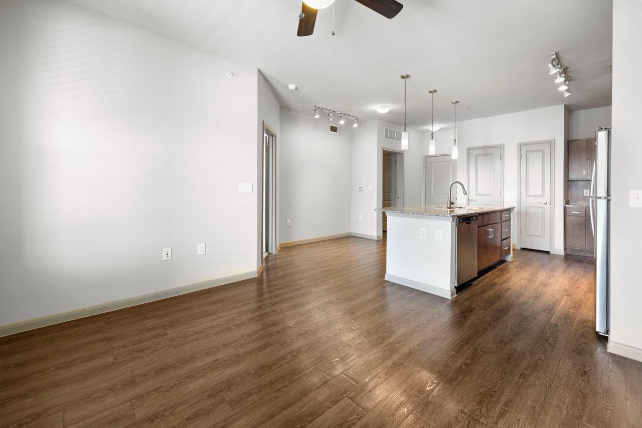 Open-concept living area with island kitchen, wooden floors, and pendant lighting.