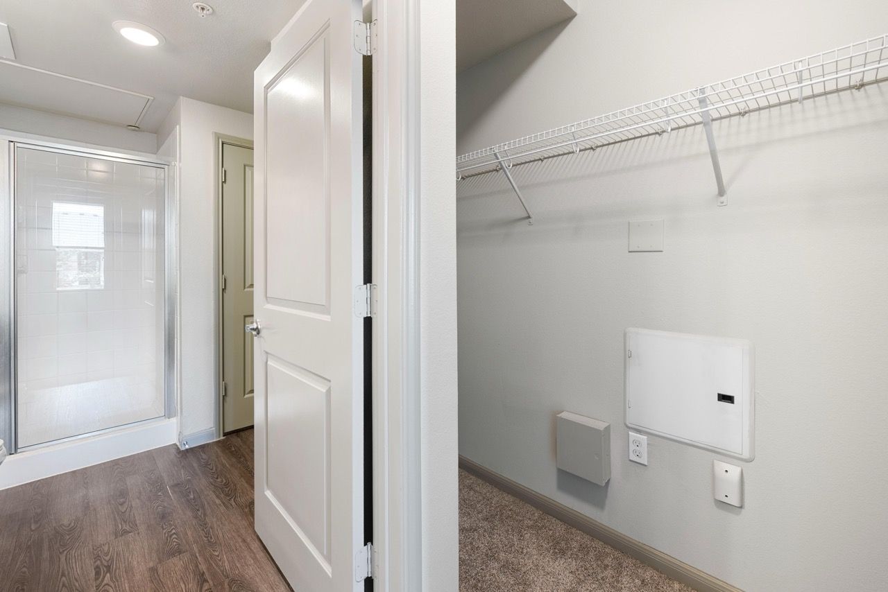 Walk-in closet with a wire shelf beside a doorway to a bathroom/shower.