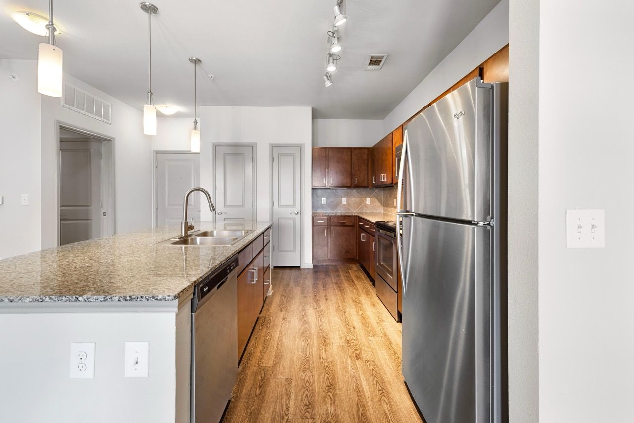 Open-concept kitchen with granite island, stainless steel appliances, and wood cabinets.