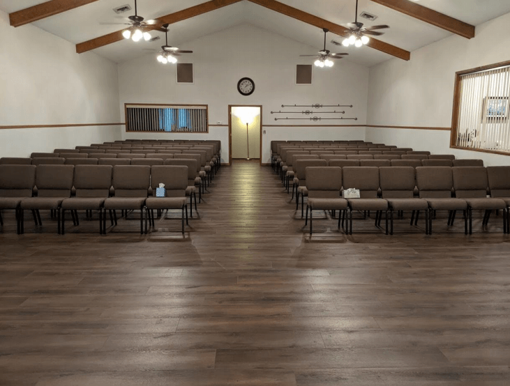 A large room with rows of chairs and a wooden floor.