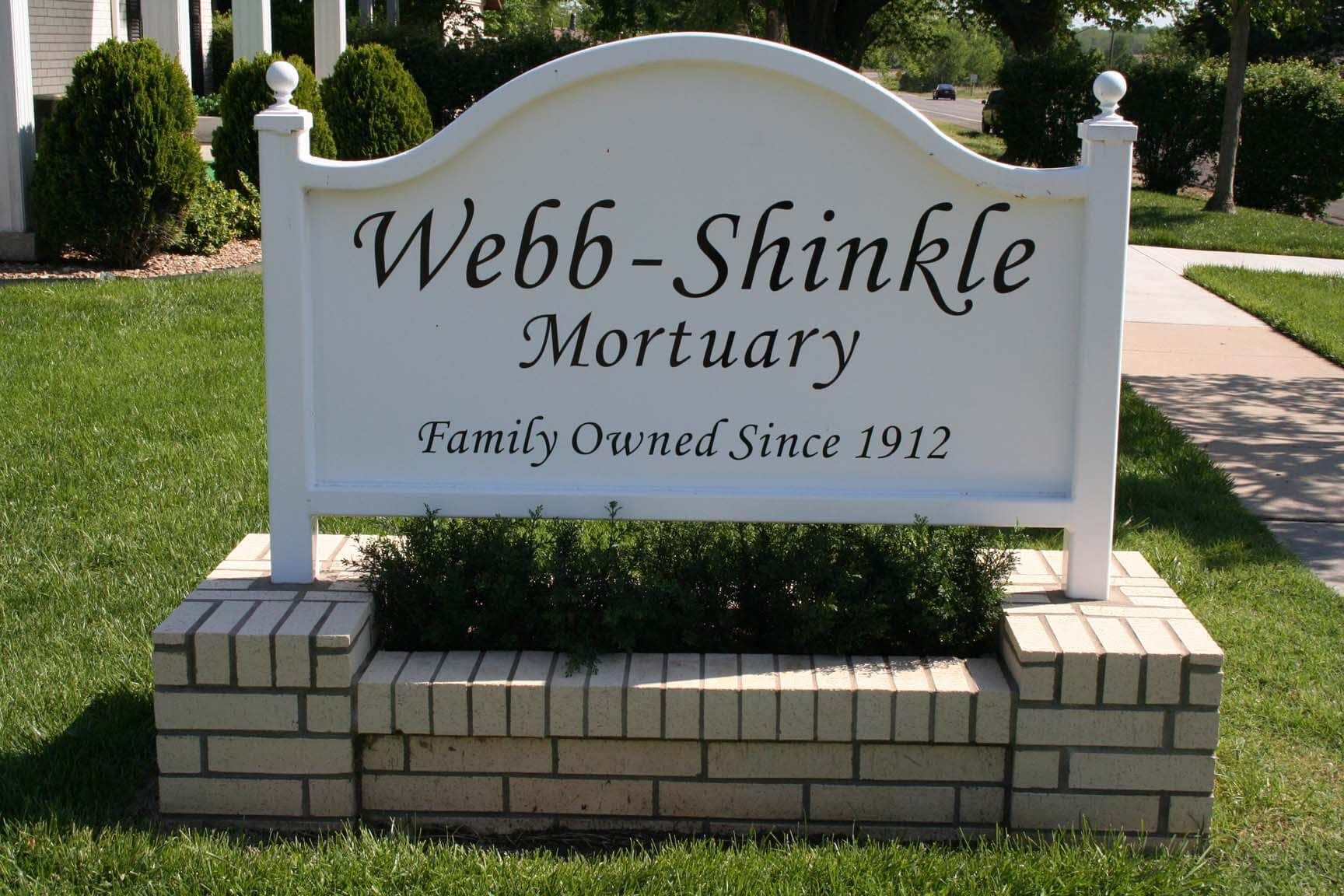 A white sign that says webb-shinkle mortuary family owned since 1912