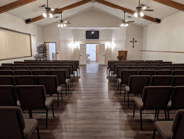 A church with rows of chairs and a cross on the wall.