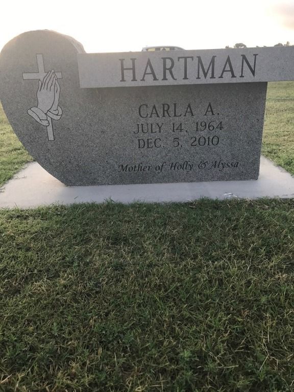 A heart shaped gravestone for carla hartman in a cemetery.