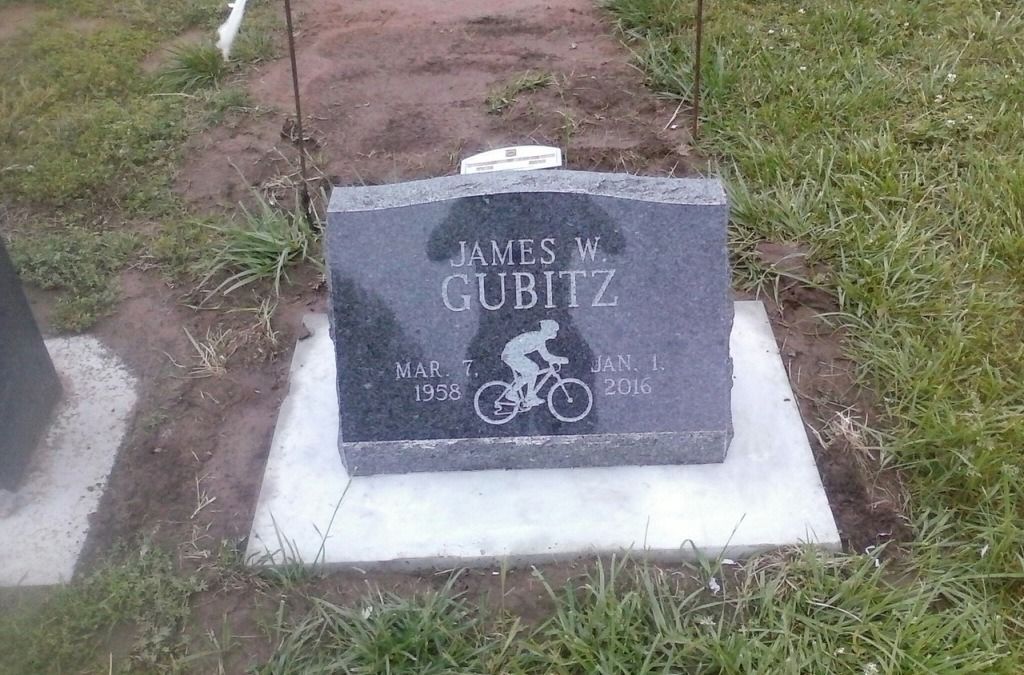 A gravestone with a picture of a man riding a bike on it.