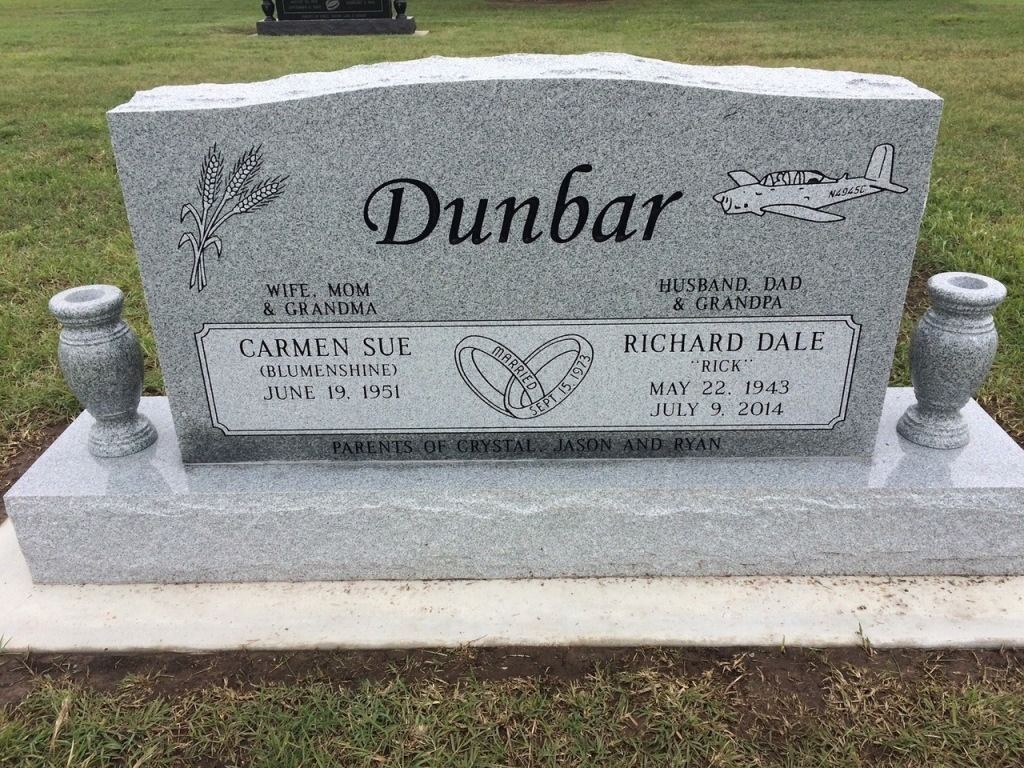 A gravestone for dunbar in a cemetery with two vases.