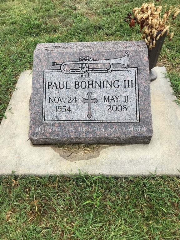A gravestone for paul bohning iii in a cemetery with a trumpet on it.