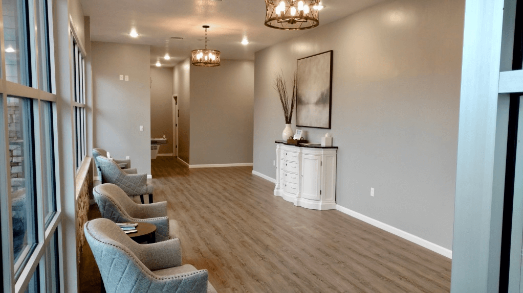 A long hallway with chairs and a chandelier.